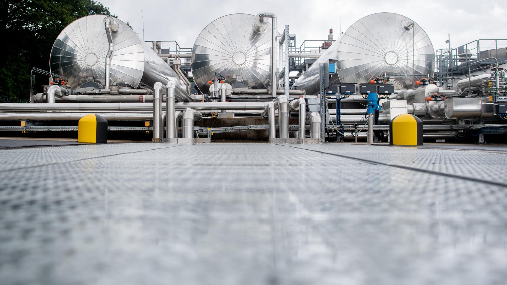 Der Blick geht direkt auf drei silberne Prozesswassertanks einer technische Anlagen zur Ein- und Ausspeicherung von Erdgas auf dem Gelände des Erdgasspeichers Rehden der SEFE Storage GmbH.