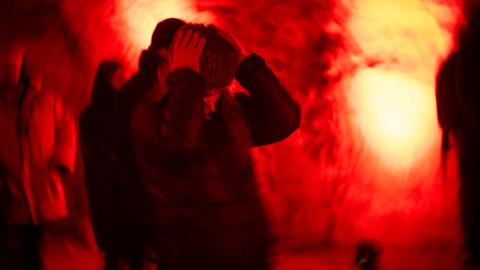Eine Frau hält sich die Ohren zu, im Hintergrund roter Nebel. Aufgenommen beim Kunstfestival Barents Spektakel in Kirkenes, Norwegen.