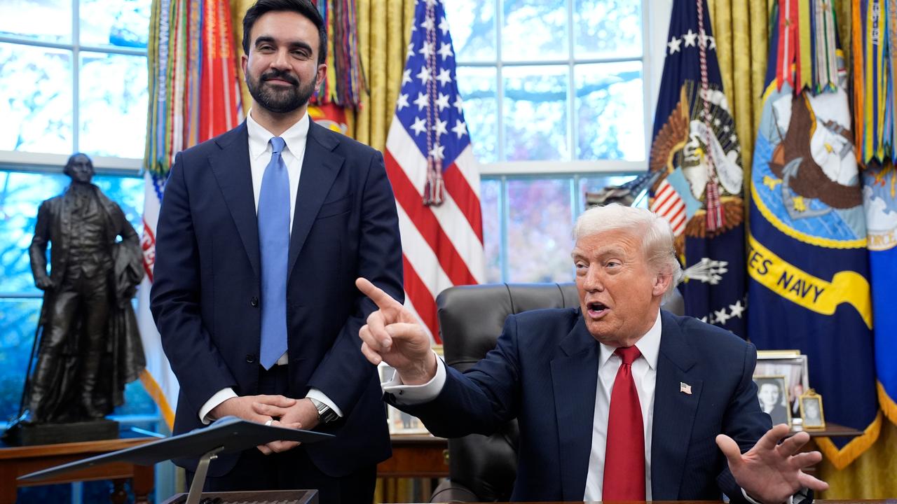 Donald Trump stzt gestikulierend am Schreibtisch im Oval Office. Neben ihm steht Zohran Mamdani und lächelt in die Kamera.