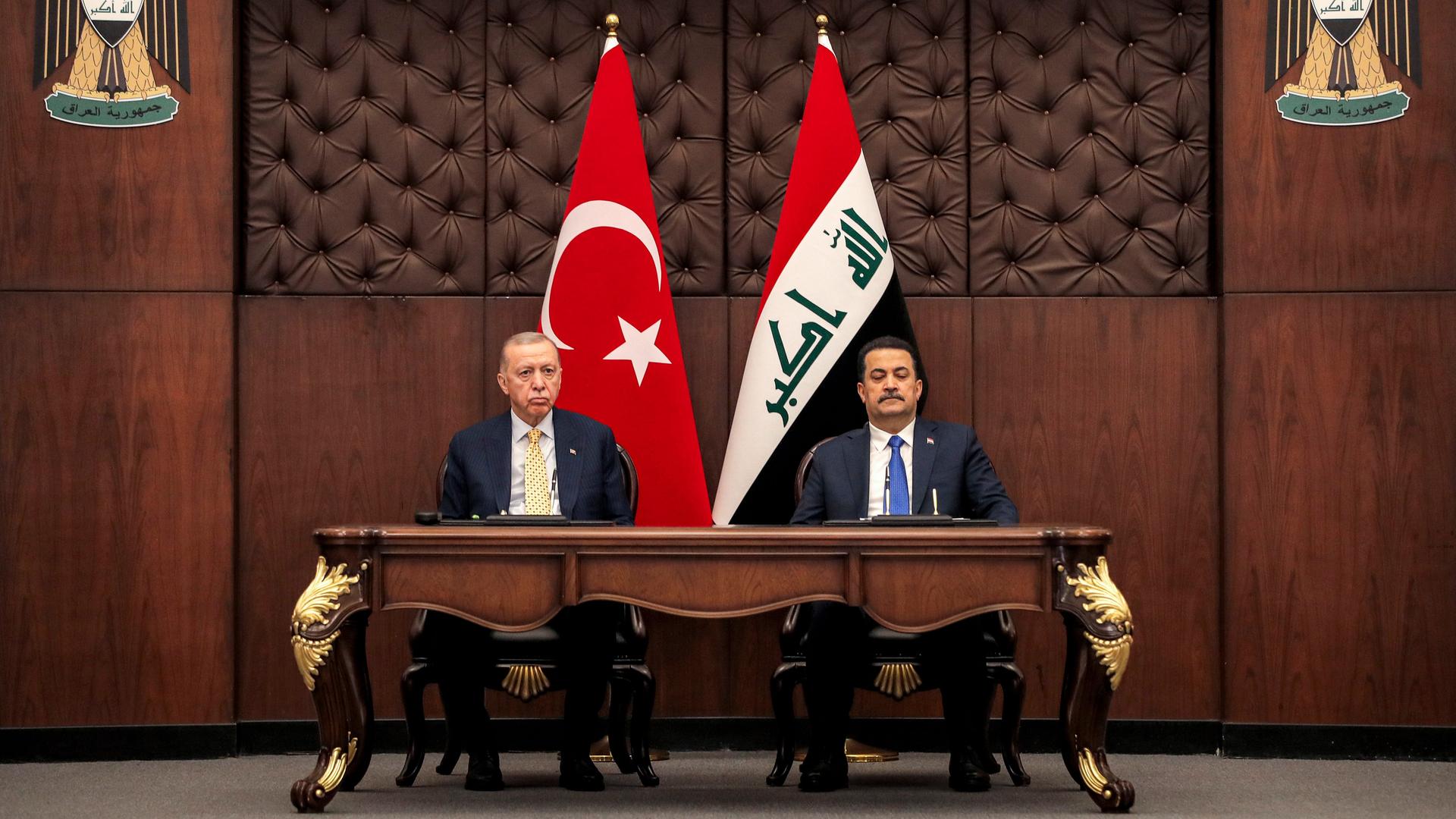 Erdogan und al-Sudani sitzen an einem Tisch mit goldener Verzierung. Im Hintergrund die Flaggen der Türkei und des Irak.