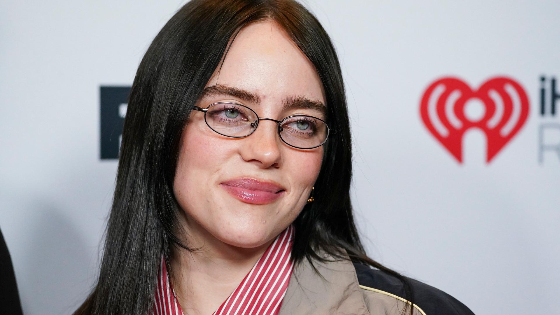 Die Popsängerin Billie Eilish guckt durch ihre Brille in die Kamera.