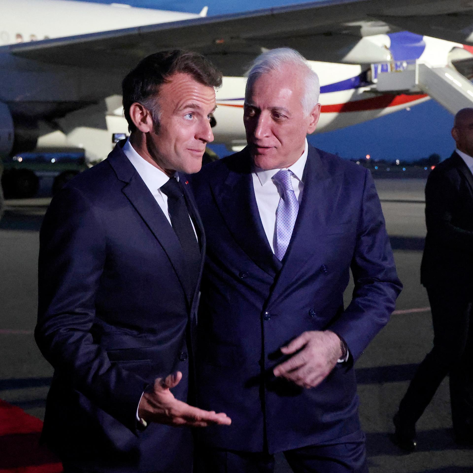 Frankreichs Präsident Emmanuel Macron an der Seite des armenischen Präsidenten Vahagn Khachaturyan. Im Hintergrund ein Flugzeug.