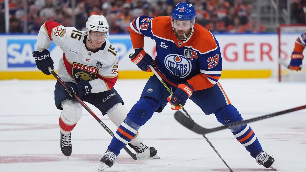 Ein Eishockeyspieler führt den Puck mit seinem Schläger und wird von einem Gegenspieler verfolgt.