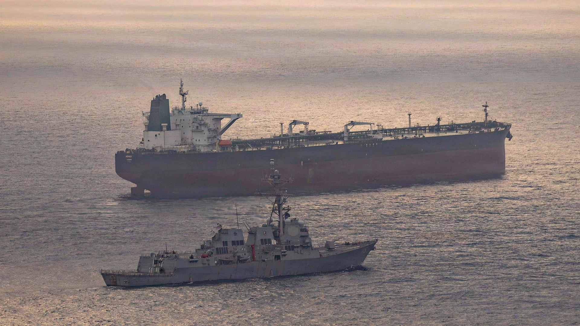 Ein US-Kriegsschiff und ein iranischer Tanker Anfang Mai in der Straße von Hormus. Auf dem Wasser spiegelt sich die untergehende Sonne. Ein US-Kriegsschiff und ein iranischer Tanker Anfang Mai in der Straße von Hormus. Auf dem Wasser spiegelt sich die untergehende Sonne.