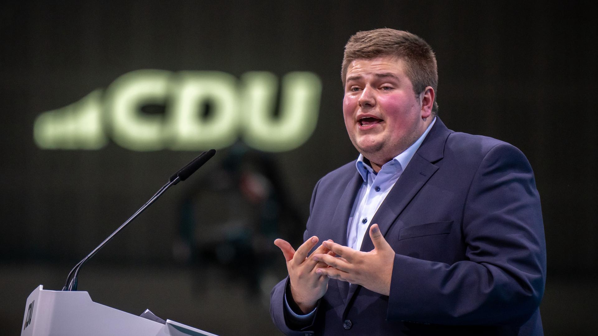 Johannes Volkmann, 27 Jahre alter Enkel von Altkanzler Kohl, spricht beim CDU-Bundesparteitag. Im Hintergrund ist das Logo der Partei leicht verschwommen zu sehen.