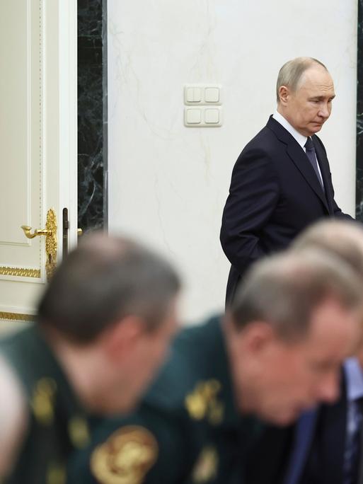 Wladimir Putin tritt an eine Zusammenkunft heran, bei der Menschen in Uniform teilnehmen. 