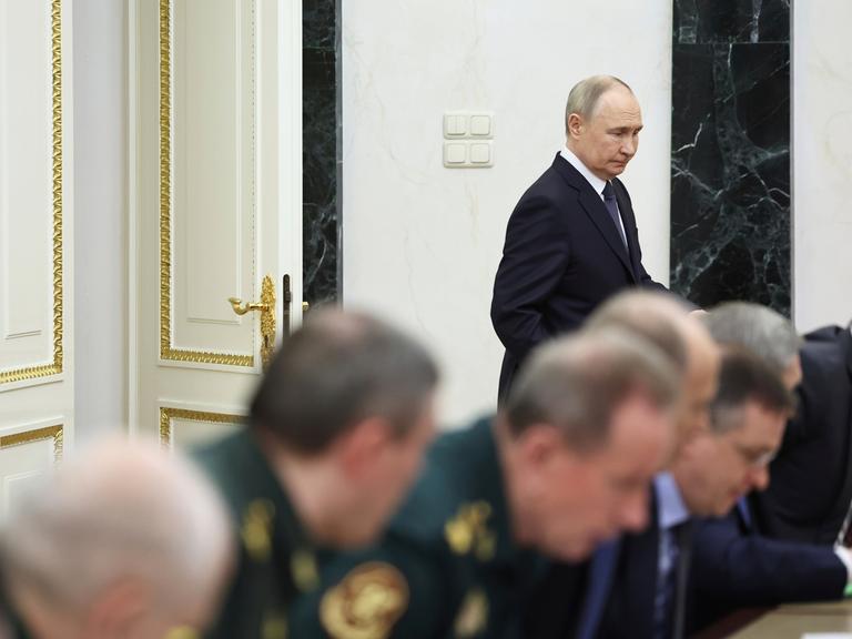 Wladimir Putin tritt an eine Zusammenkunft heran, bei der Menschen in Uniform teilnehmen. 