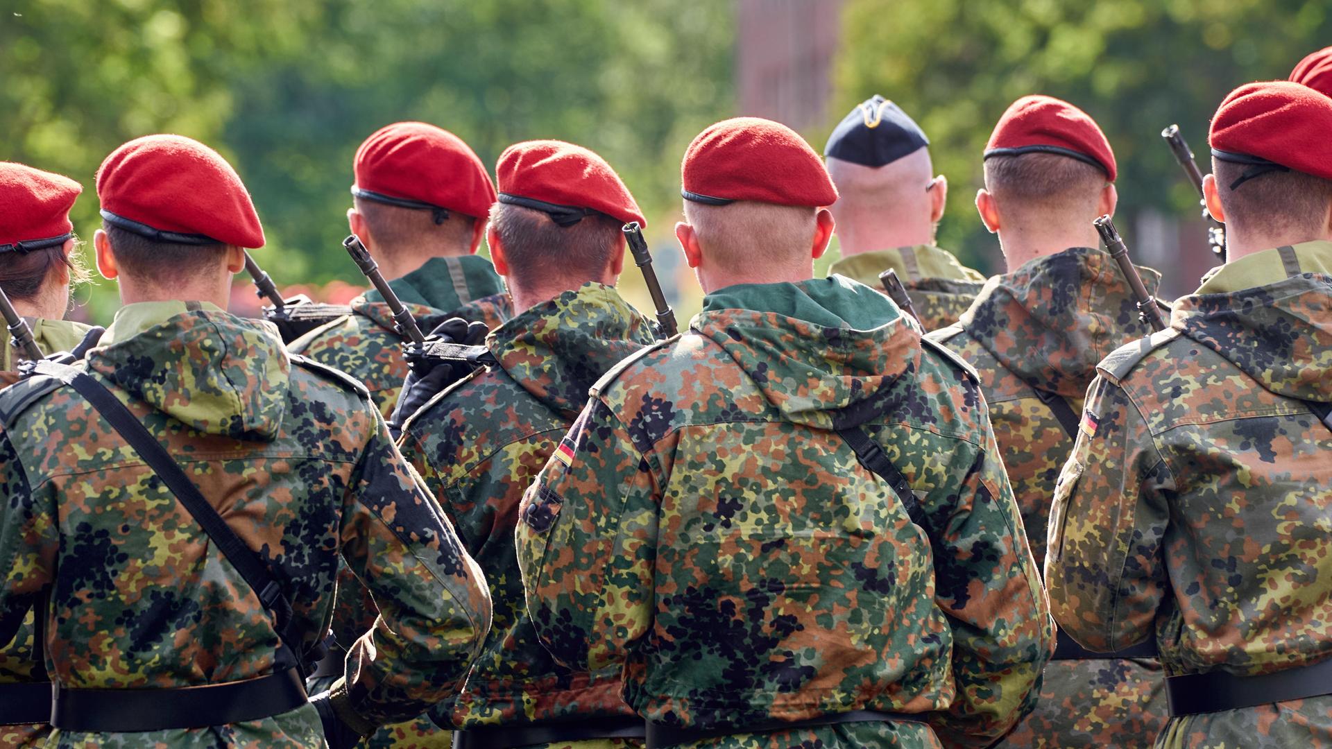 Eine Gruppe von Soldaten der Deutschen Bundeswehr in Tarnuniformen stehen in Formation mit Gewehr bewaffnet bei einem Appell.