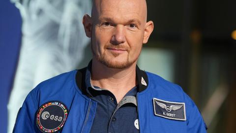 Astronaut Alexander Gerst im blauen Overall mit einem Aufnäher der "esa" und seinem Namen