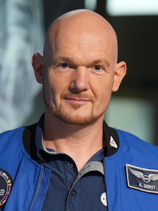 Astronaut Alexander Gerst im blauen Overall mit einem Aufnäher der "esa" und seinem Namen