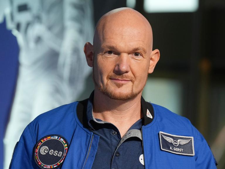 Astronaut Alexander Gerst im blauen Overall mit einem Aufnäher der "esa" und seinem Namen