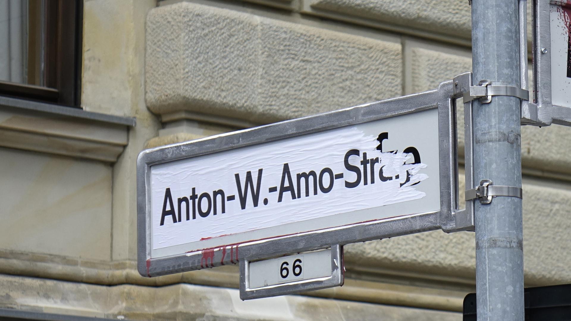 Strassenschild der Anton-Wilhelm-Amo-Straße, daneben ein Strassenschild, was nicht zu erkennen ist weil es besprüht ist