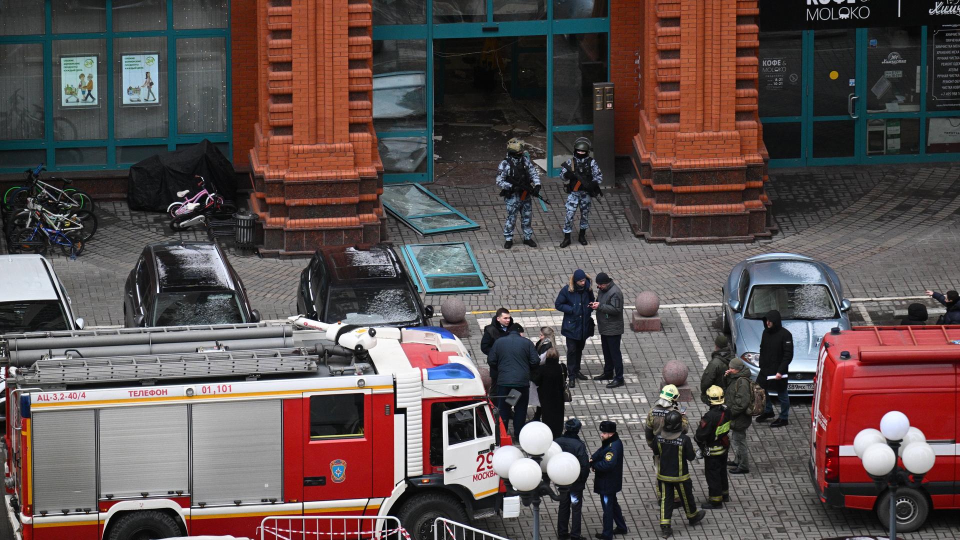 Feuerwehrleute stehen vor dem Wohnkomplex in Moskau, in dem es eine Bombenexplosion gab. Einige Fenster sind zerborsten und liegen auf der Straße.