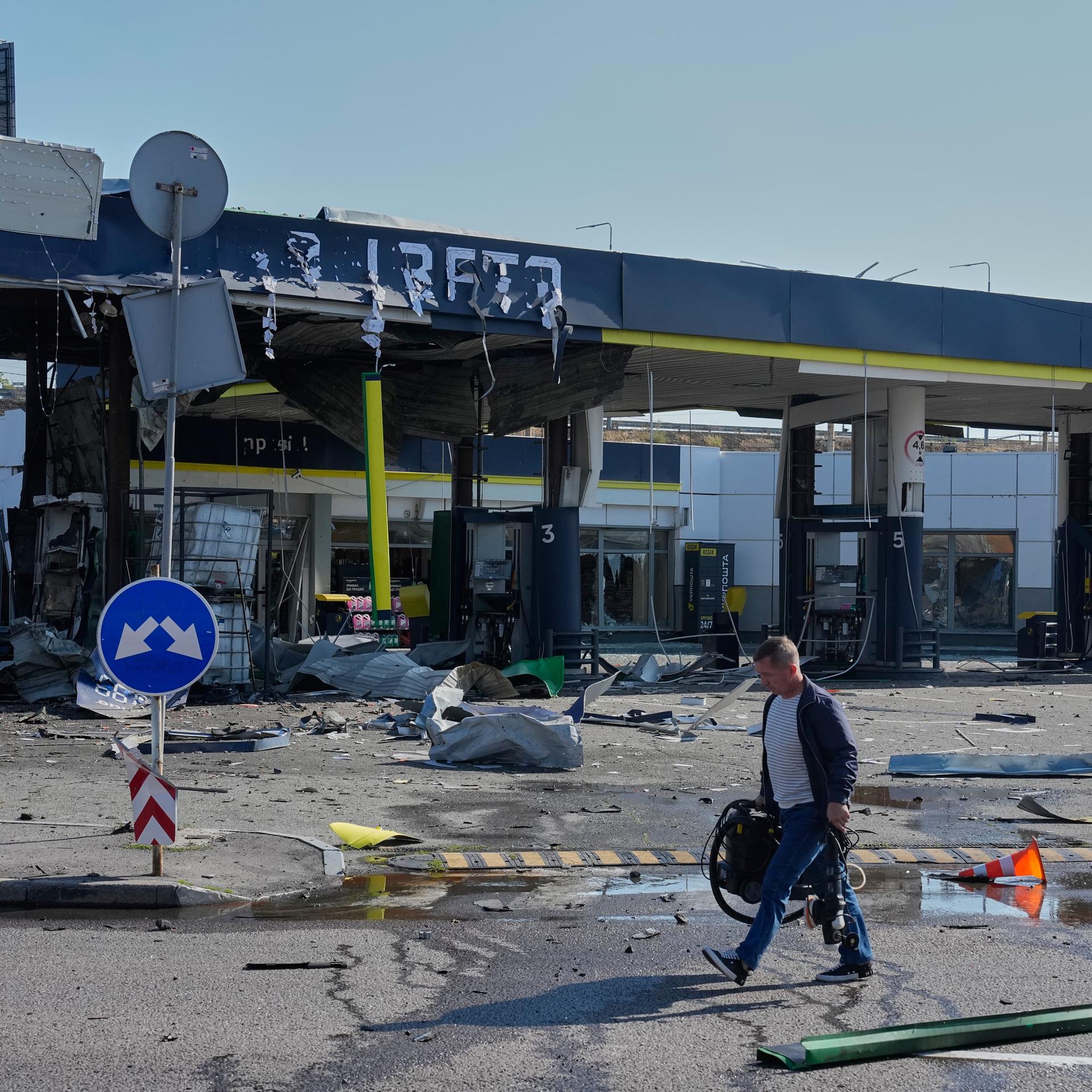 Ein Arbeiter geht an einer völlig zerstörten Tankstelle in der Region Kiew vorbei.