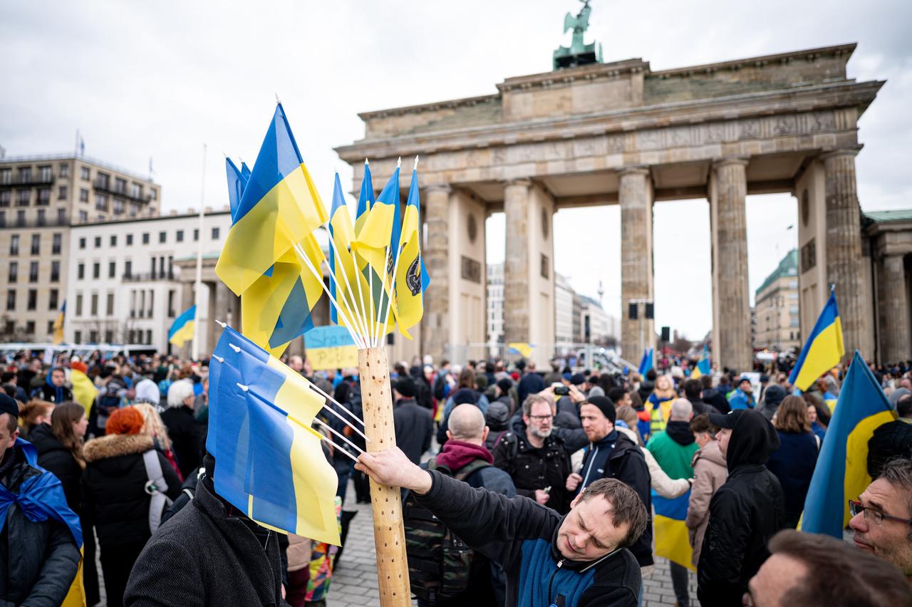 Menschen nehmen vor dem Brandenburger Tor an einer Solidaritätsdemonstration teil. Viele von ihnen tragen ukrainische Fahnen. Menschen nehmen vor dem Brandenburger Tor an einer Solidaritätsdemonstration teil. Viele von ihnen tragen ukrainische Fahnen.