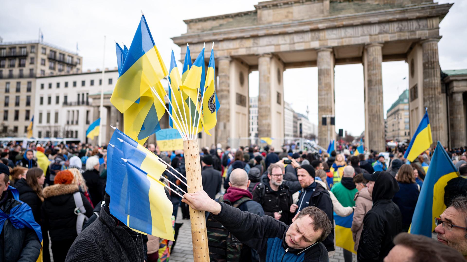 Menschen nehmen vor dem Brandenburger Tor an einer Solidaritätsdemonstration teil. Viele von ihnen tragen ukrainische Fahnen.