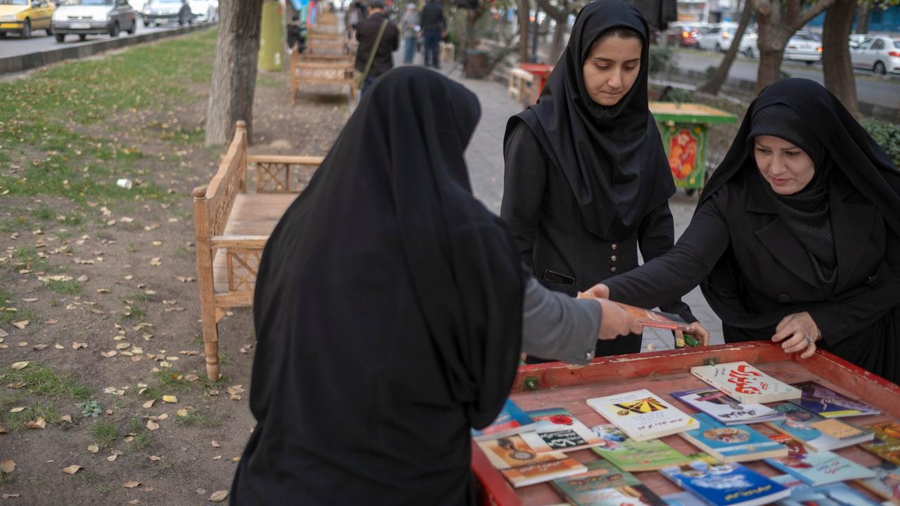 Iranische Frauen betrachten Bücher während einer Veranstaltung in einer Fußgängerzone im Zentrum von Teheran