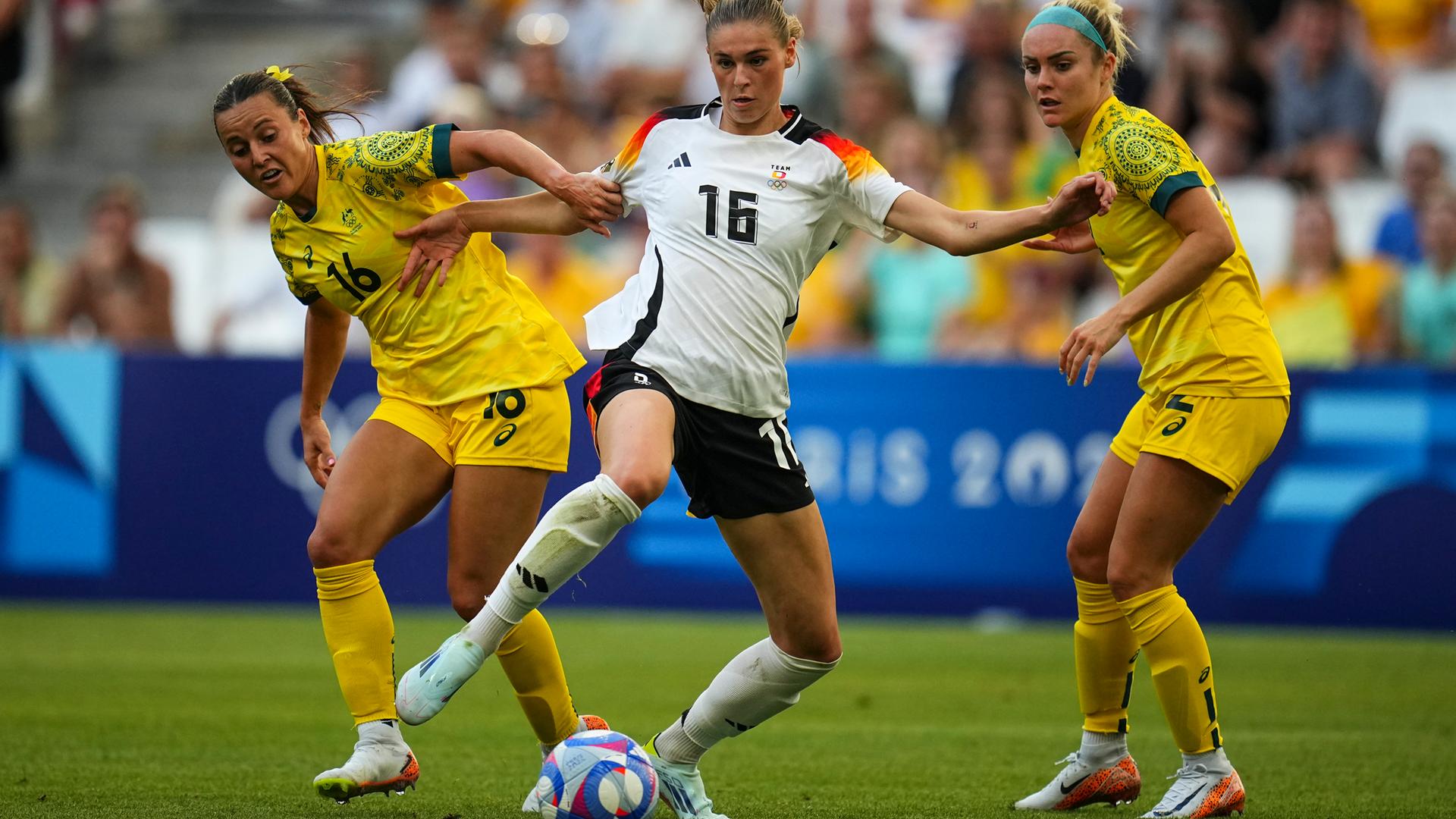 Das Bild zeigt eine Szene aus Olympia-Frauen-Fußballspiel Deutschland gegen Australien: Deutschlands Jule Brand kämpft gegen Australiens Hayley Raso und Ellie Carpenter um den Ball. 