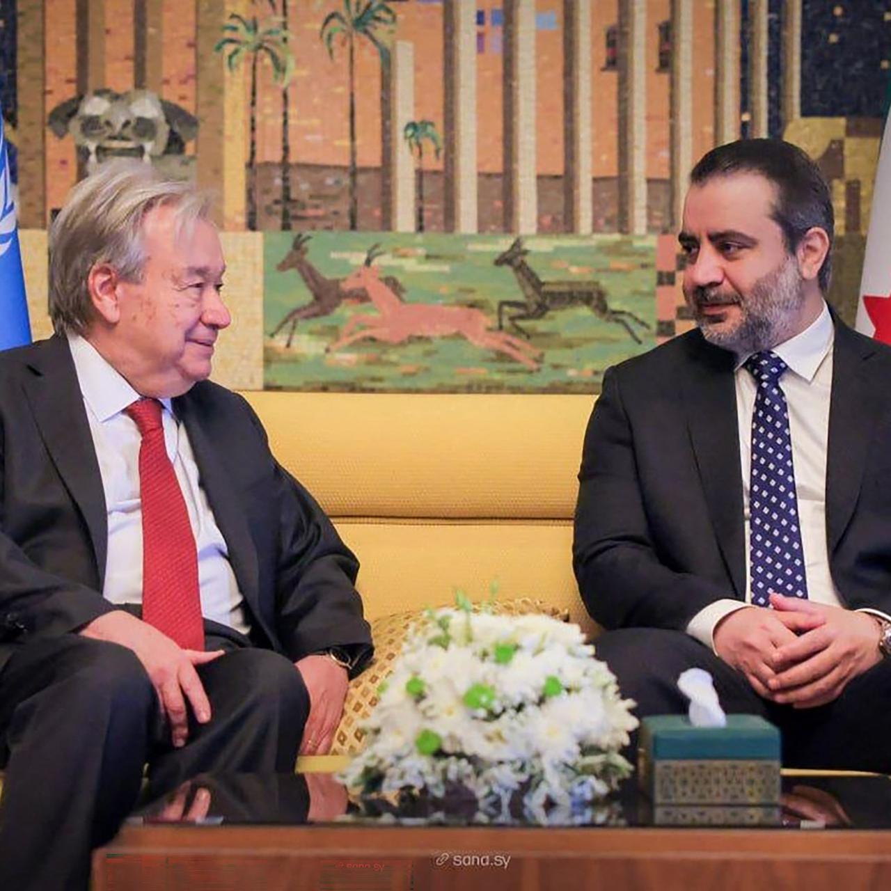 UNO-Generalsekretär Antonio Guterres (li.) und der syrische Außenminister Asaad al-Schaibani sitzen nebeneinander auf einem beigefarbenen Sofa.