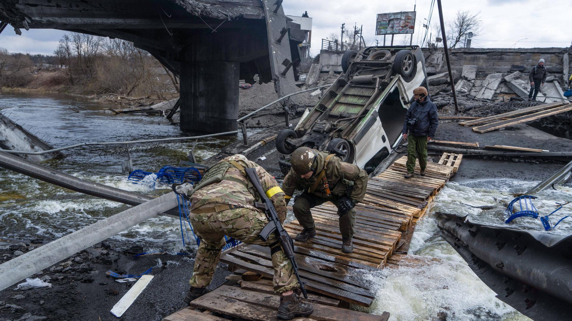 Ukrainische Soldaten richten einen Weg unter einer zerstörten Brücke in Irpin ein, um der Bevölkerung die Evakuierung von der Frontlinie zu ermöglichen.