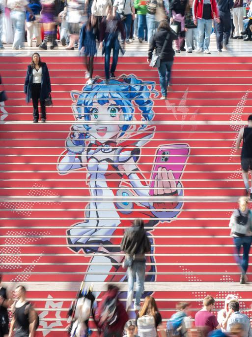 Eine rote Treppe mit einer Manga-Zeichnung und Menschen