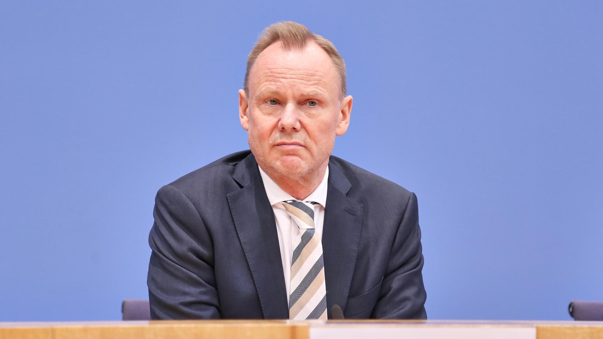 Andy Grote sitzt im Saal der Bundespressekonferenz. Vor ihm ist ein Holztisch zu sehen, im Hintergrund eine blaue Wand. Er trägt ein dunkles Jackett und blickt ernst in die Kamera. Andy Grote sitzt im Saal der Bundespressekonferenz. Vor ihm ist ein Holztisch zu sehen, im Hintergrund eine blaue Wand. Er trägt ein dunkles Jackett und blickt ernst in die Kamera.