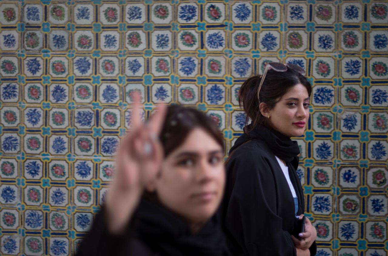 Zwei junge iranische Frauen, die kein Kopftuch tragen, beim Besuch des Golestan-Palastes im Süden Teherans: Eine der Frauen formt mit den Fingern ein V und zeigt das "Victory"-Zeichen