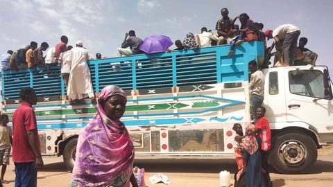 Das Foto zeigt Menschen im Sudan, die auf einen Lastwagen steigen, um zu fliehen.