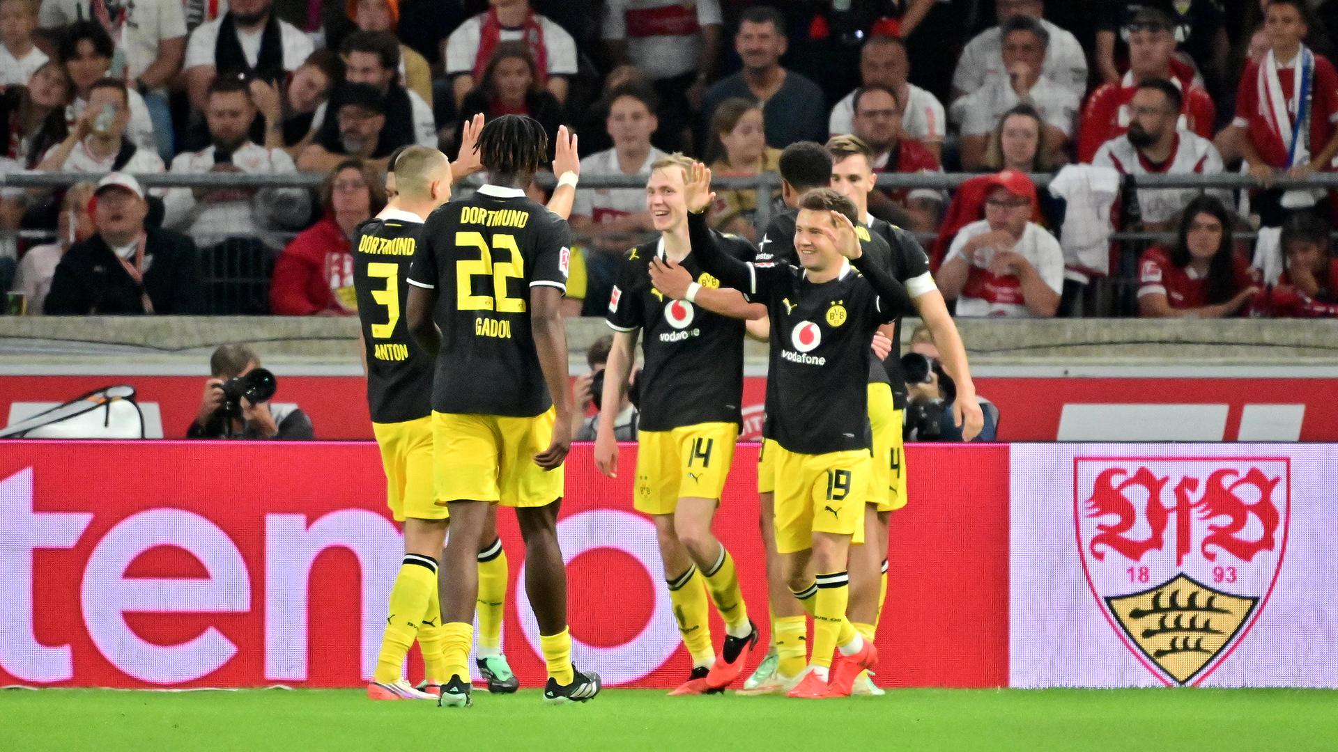 Spieler von Borussia Dortmund jubeln in schwarzen Trikots und gelben Hosen. 