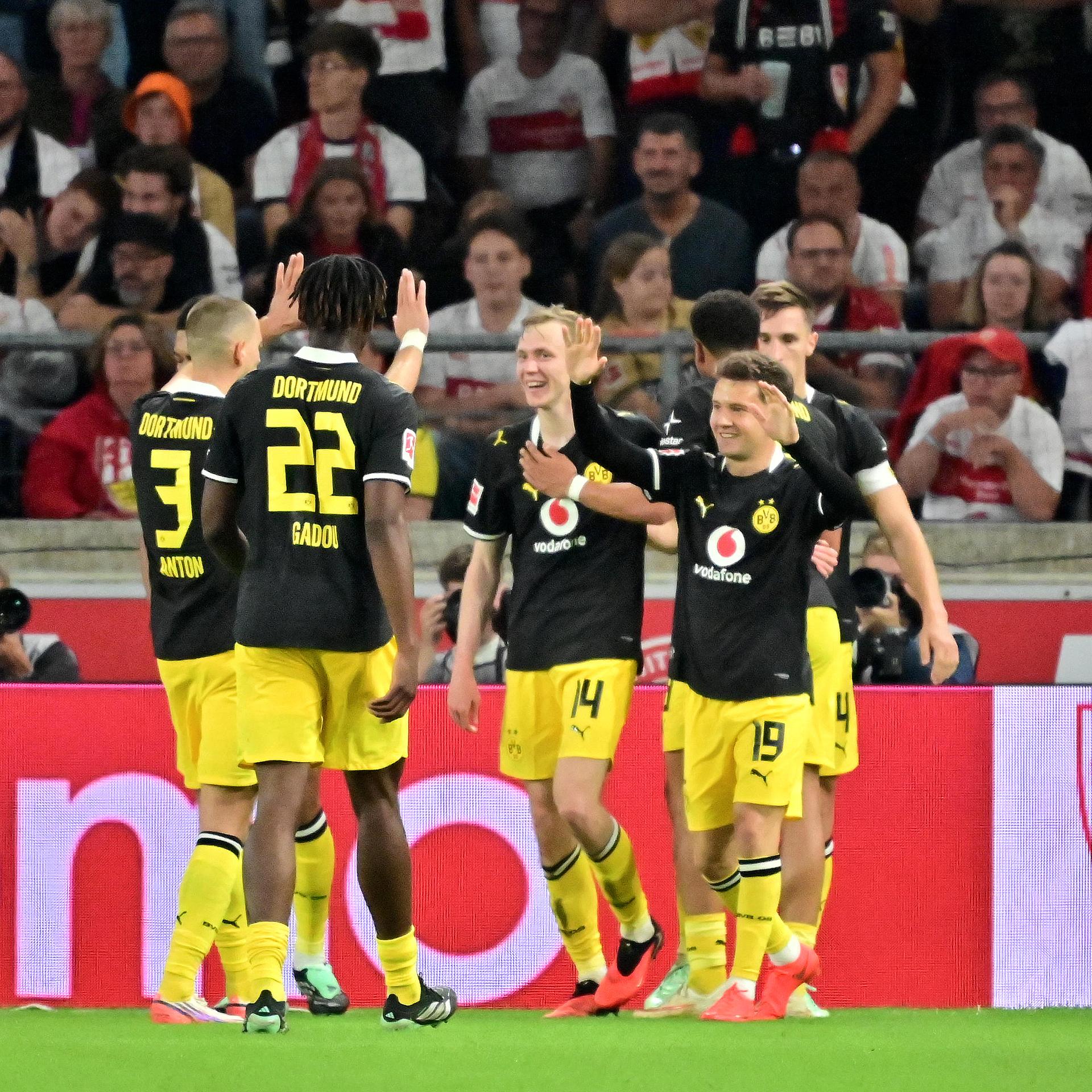 Spieler von Borussia Dortmund jubeln in schwarzen Trikots und gelben Hosen. 