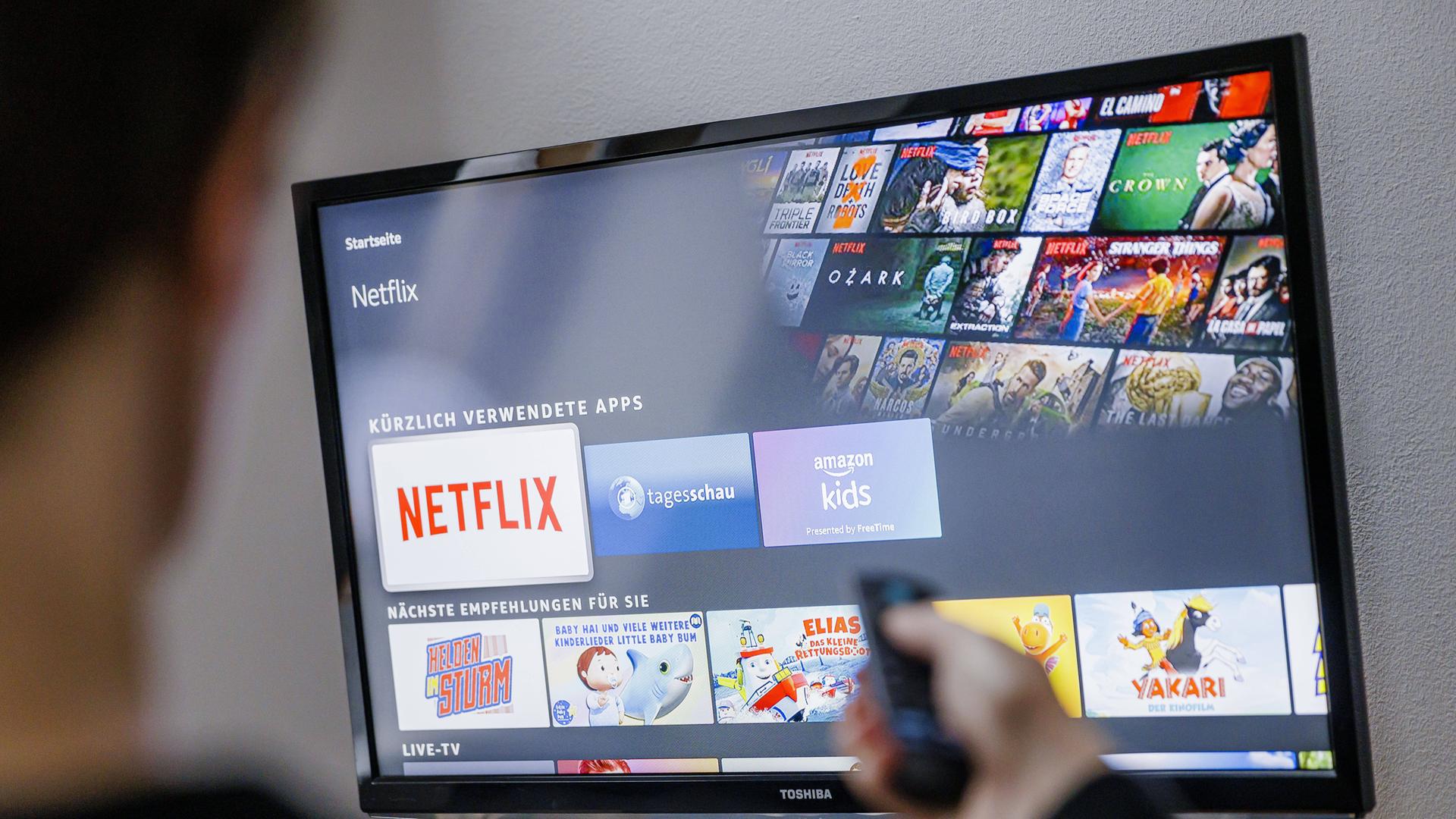 Auf einem TV-Bildschirm sind Logos von Medienplattformen zu sehen, darunter hervorgehoben dasjenige von Netflix.