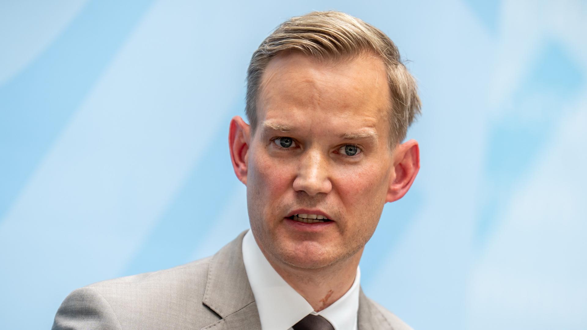 Das Bild zeigt Streecks Kopf vor einer hellblauen Wand. Er blickt ernst.