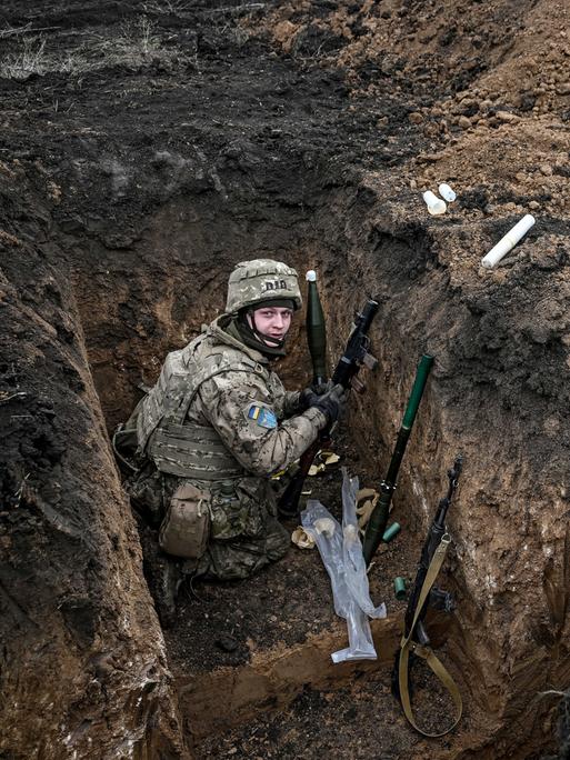 Zwei Soldaten der 110. Territorialverteidigungsbrigade befinden sich in einem Schützengraben in der Region Saporischschja im Südosten der Ukraine. Sie tragen Tarnuniformen, Helme und Schutzwesten. 