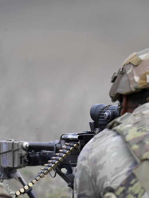 Ein Soldat visiert mit seinem Maschinengewehr ein Ziel an. Er trainiert im Oktober 2024 in einer NATO-Militärbasis in Rumänien. 