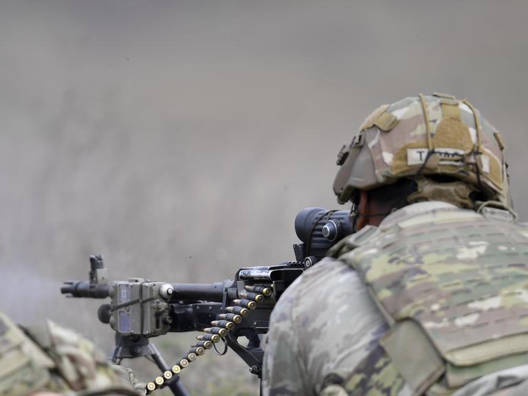 Ein Soldat visiert mit seinem Maschinengewehr ein Ziel an. Er trainiert im Oktober 2024 in einer NATO-Militärbasis in Rumänien. 