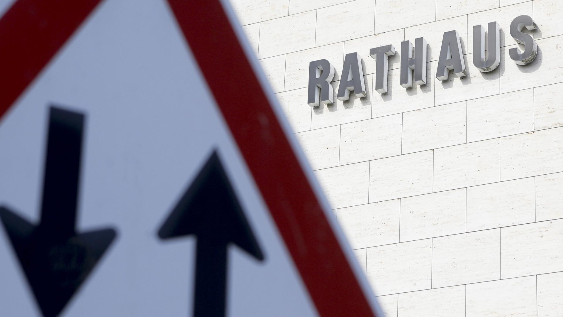 Ein Verkehrsschild mit einem Pfeil nach oben und nach unten ist vor einem Gebäude mit dem Schriftzug "Rathaus" zu sehen.