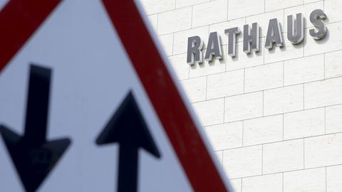 Ein Verkehrsschild mit einem Pfeil nach oben und nach unten ist vor einem Gebäude mit dem Schriftzug "Rathaus" zu sehen.