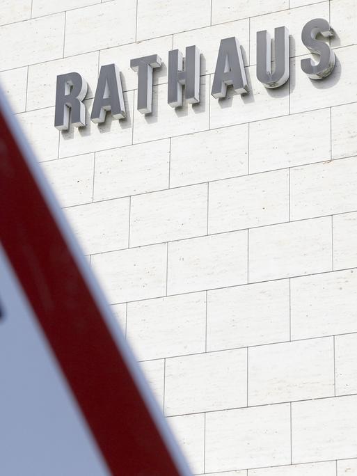 Ein Verkehrsschild mit einem Pfeil nach oben und nach unten ist vor einem Gebäude mit dem Schriftzug "Rathaus" zu sehen.