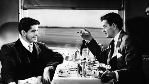 Auf einer Zugreise lernt Guy Haines einen Mann kennen, der ihm einen unglaublichen Handel vorschlägt. . Ausschnitt aus dem Film von Alfred Hitchcock aus dem Jahr 1951 mit den Schauspielern Farley Granger & Robert Walker. Zu sehen: Eine Szene in einem Speisewagen. 