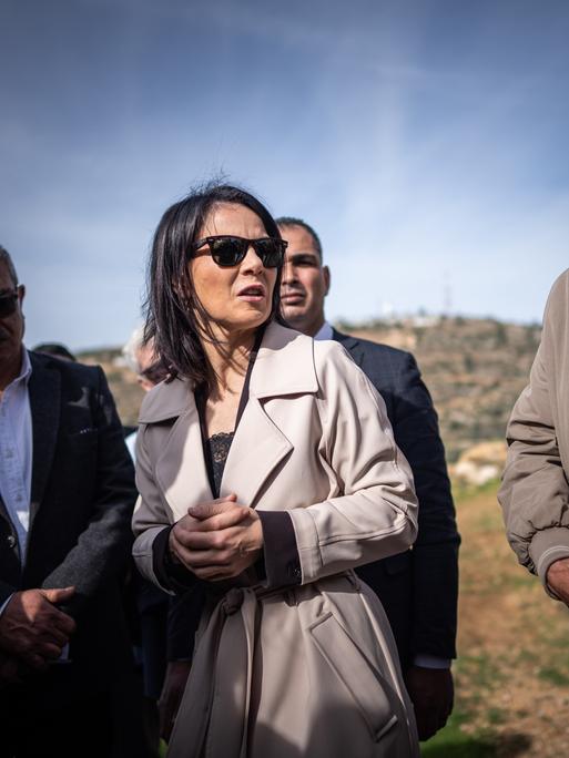 Annalena Baerbock (Bündnis90/Die Grünen) spricht im Westjordanland mit durch Siedlergewalt vertriebenen palästinensischen Bewohnern. Im Hintergrund ein karger Hügel.