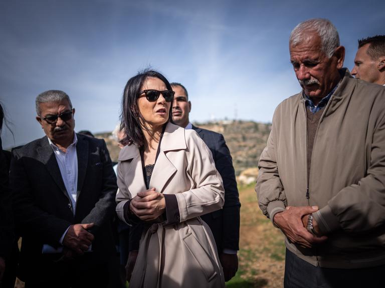 Annalena Baerbock (Bündnis90/Die Grünen) spricht im Westjordanland mit durch Siedlergewalt vertriebenen palästinensischen Bewohnern. Im Hintergrund ein karger Hügel.