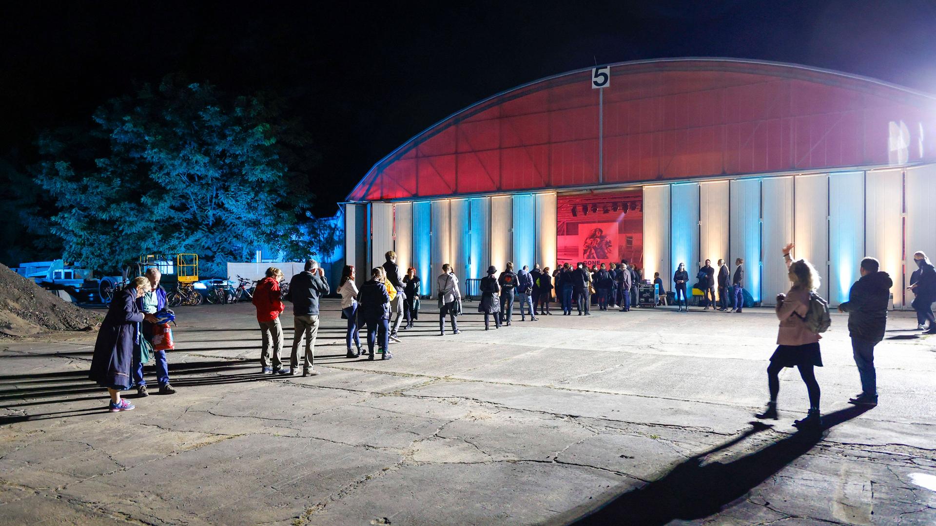 Menschen warten vor einer Halle auf Einlass. Menschen warten vor einer Halle auf Einlass.