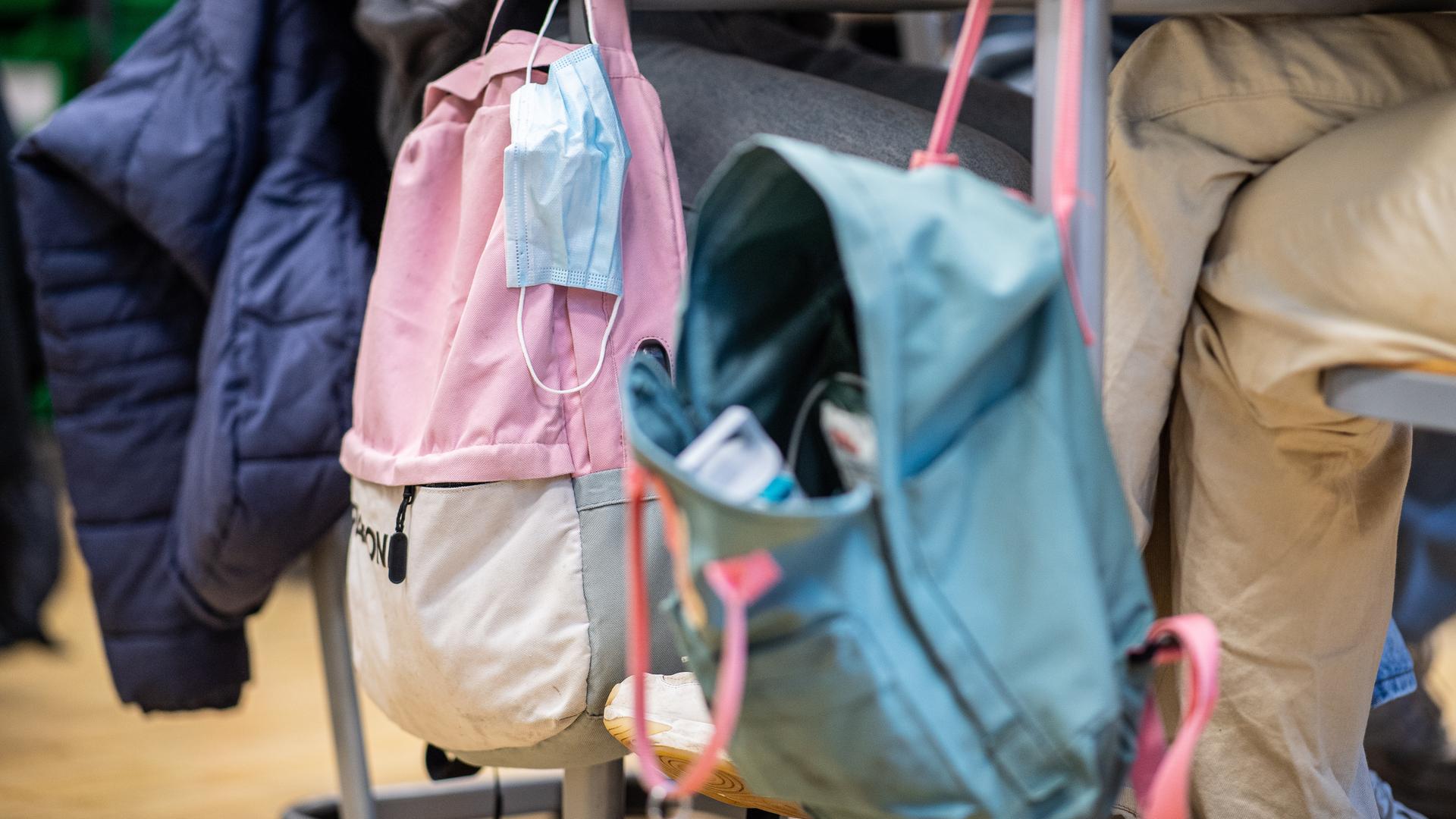 An einem Klassentisch hängt neben einem Rucksack eine Mund-Nasenbedeckung.