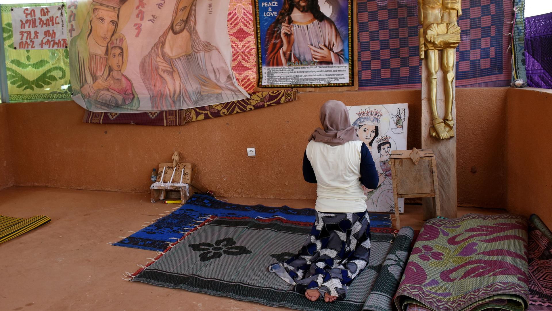Eine junge katholische Flüchtlingsfrau betet in einer improvisierten Kirche im Durchgangslager des Flüchtlingshilfswerks der Vereinten Nationen (UNHCR) in Niger. 