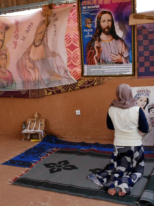 Eine junge katholische Flüchtlingsfrau betet in einer improvisierten Kirche im Durchgangslager des Flüchtlingshilfswerks der Vereinten Nationen (UNHCR) in Niger. Eine junge katholische Flüchtlingsfrau betet in einer improvisierten Kirche im Durchgangslager des Flüchtlingshilfswerks der Vereinten Nationen (UNHCR) in Niger.