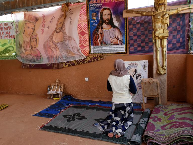 Eine junge katholische Flüchtlingsfrau betet in einer improvisierten Kirche im Durchgangslager des Flüchtlingshilfswerks der Vereinten Nationen (UNHCR) in Niger. 