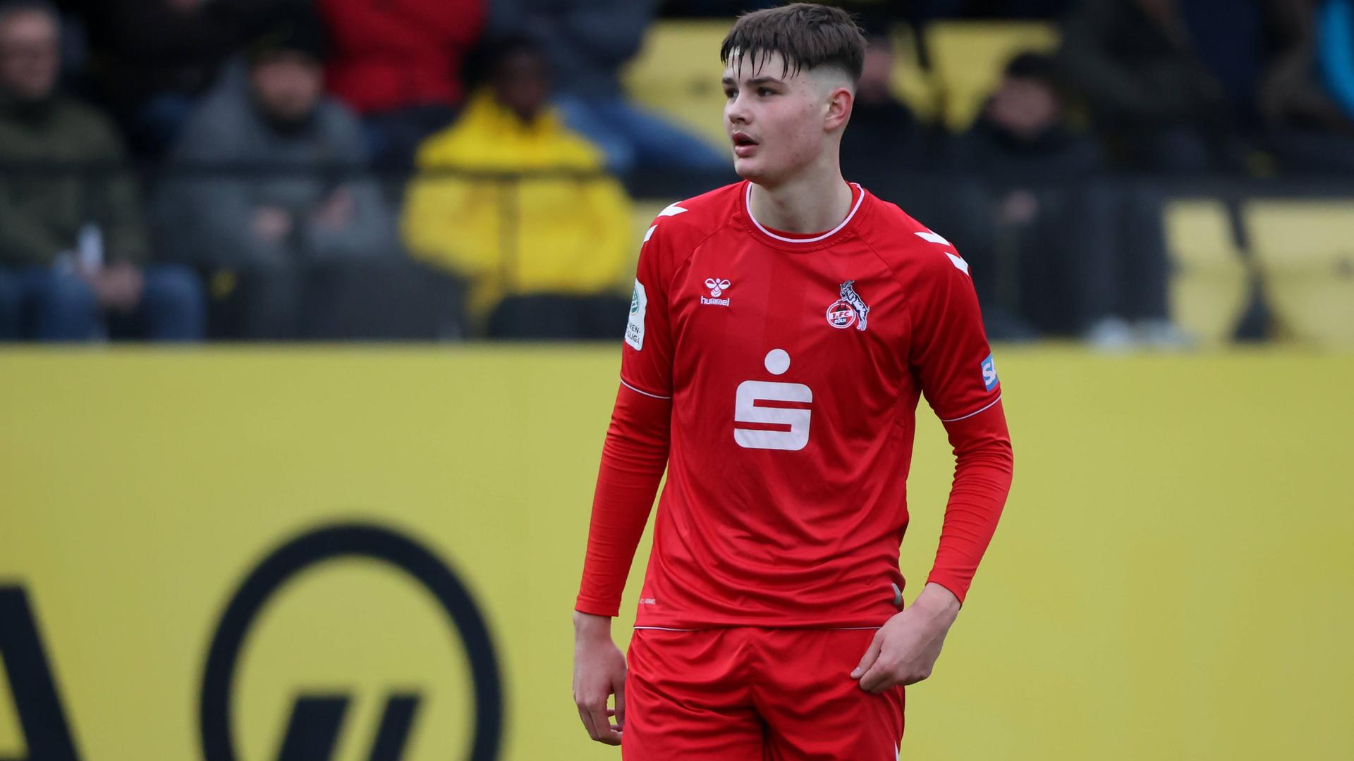U19-Stürmer Jaka Cuber Potocnik vom 1. FC Köln steht in rotem Trikot des 1. FC Köln auf dem Fußballplatz.