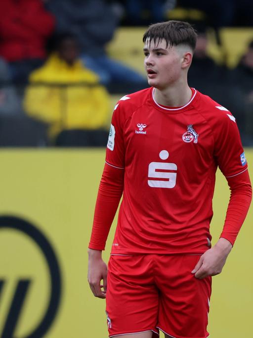 U19-Stürmer Jaka Cuber Potocnik vom 1. FC Köln steht in rotem Trikot des 1. FC Köln auf dem Fußballplatz.
