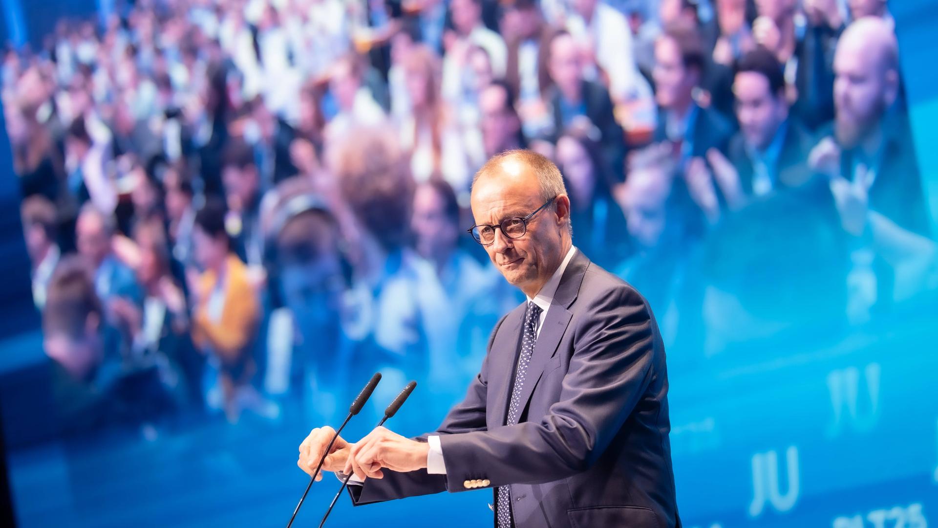Friedrich Merz steht am Mikrofon, im Hintergrund sieht man zahlreiche Menschen. Friedrich Merz steht am Mikrofon, im Hintergrund sieht man zahlreiche Menschen.