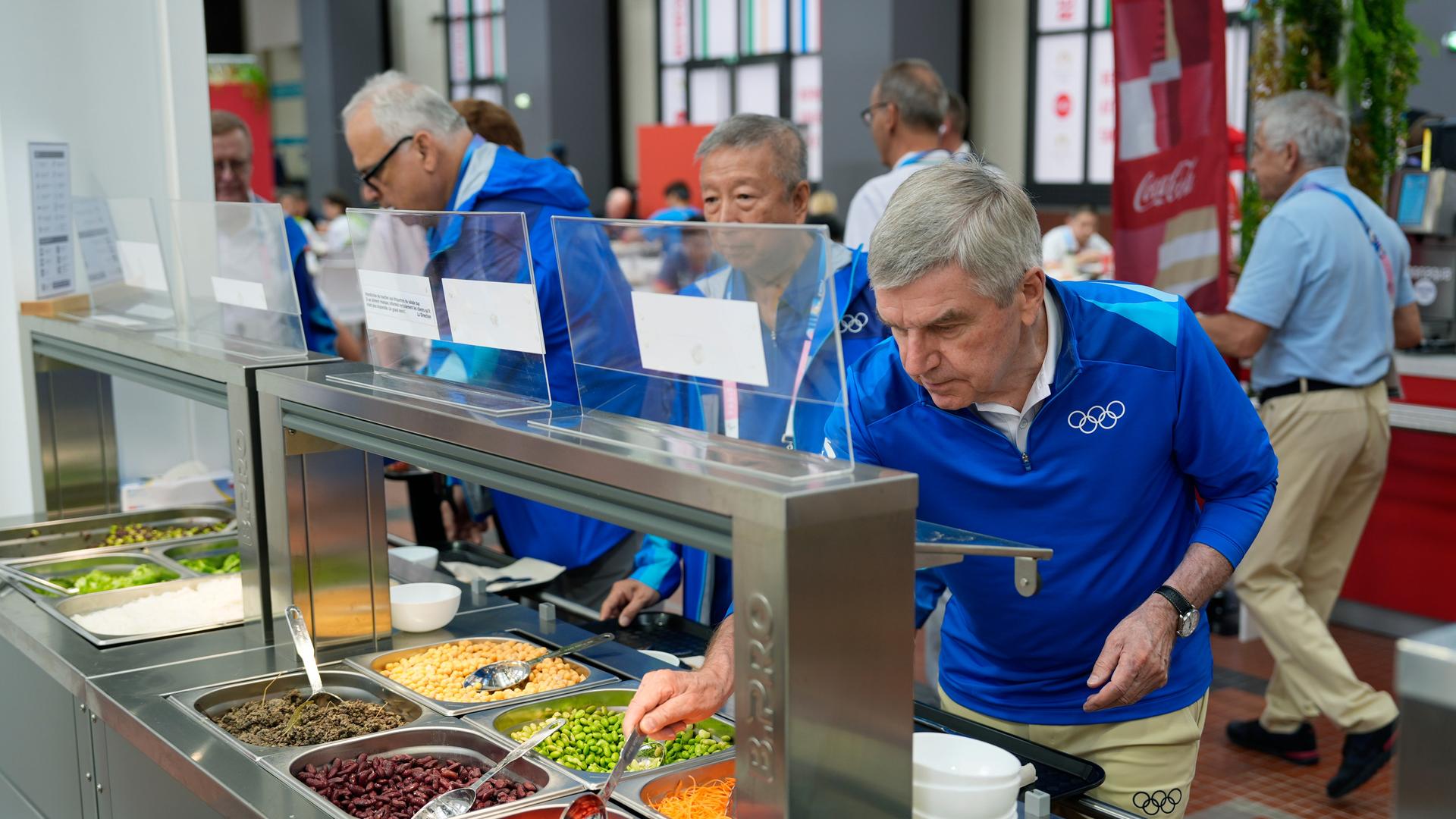 IOC-Präsident Thomas Bach an einem Salatbuffet.